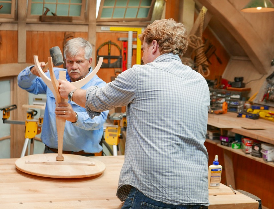 Two craftsmen shaping wood in a workshop